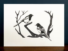 Load image into Gallery viewer, Two for joy magpies giclée print in a black frame, standing on a wooden surface with navy blue wall behind.