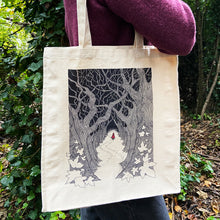 Load image into Gallery viewer, Red Riding Hood ilustration canvas tote bag being carried over the shoulder by a woman in a purple jumper in the woods.