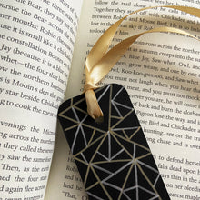Load image into Gallery viewer, Black bookmark with gold and silver geometric pattern design and a gold ribbon on an open book.