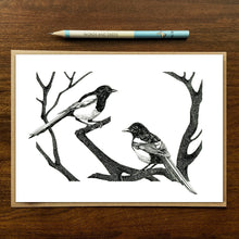 Load image into Gallery viewer, magpies greetings card on wood background with recycled kraft envelope and pencil.

