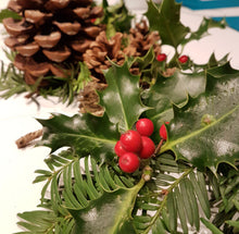 Load image into Gallery viewer, A close-up of a holly branch with glossy green leaves and bright red berries, arranged with pine cones and evergreen branches on a white surface.
