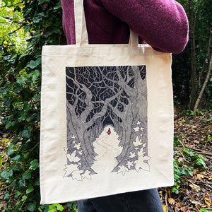Red Riding Hood ilustration canvas tote bag being carried over the shoulder by a woman in a purple jumper in the woods.