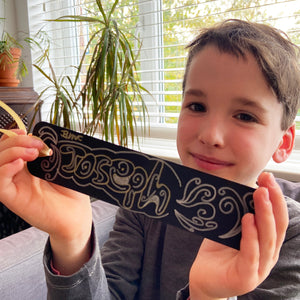 A boy shows his bookmark design proudly.