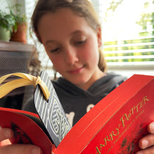 Load image into Gallery viewer, Girl reading a Harry Potter book with a bookmark inside, with a gold ribbon.
