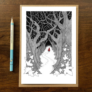 Red Riding Hood greetings card on wooden background with recycled kraft envelope and pencil.